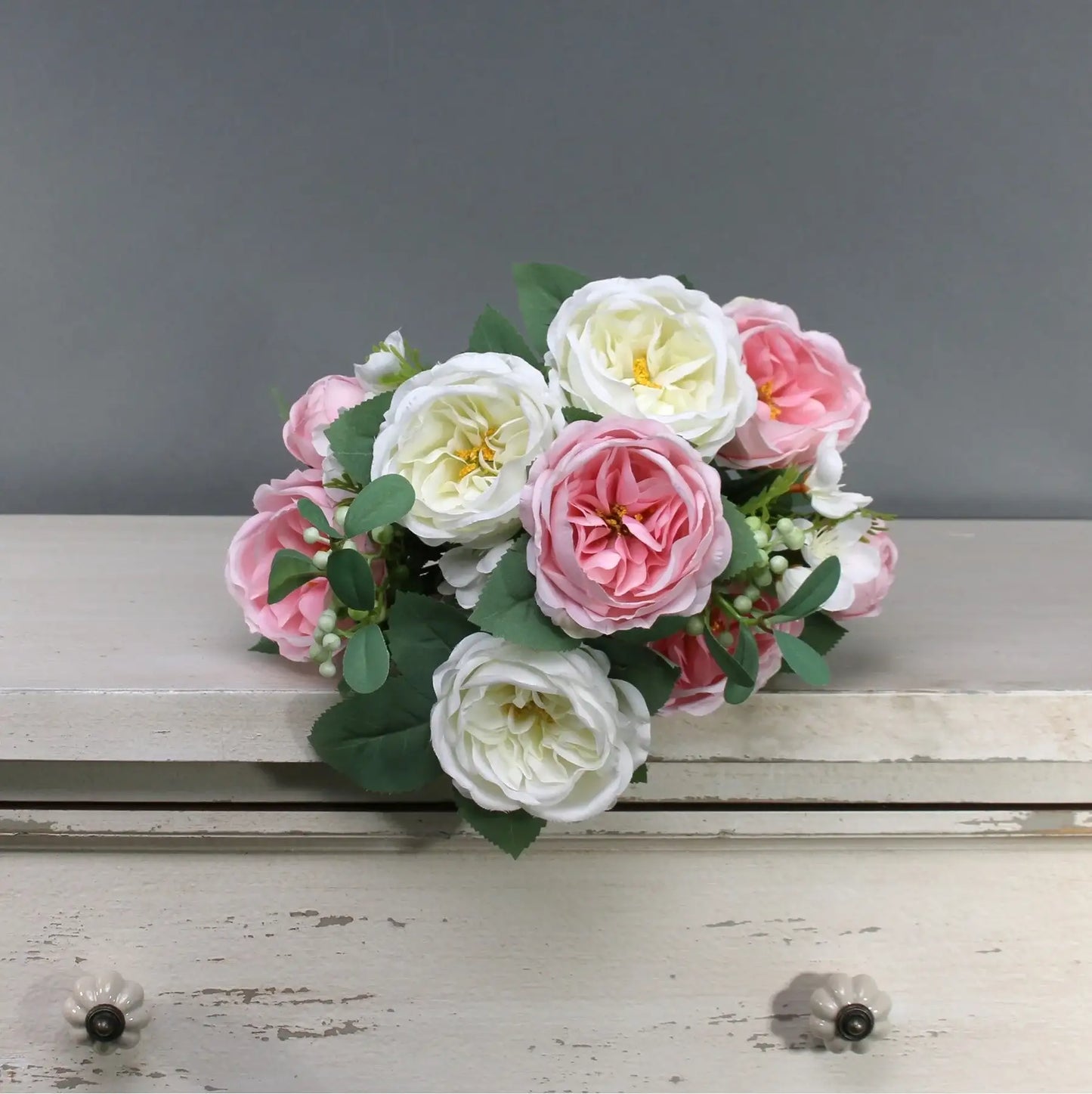 Pink and white artificial roses with green leaves on rustic dresser, perfect for home décor or gift
