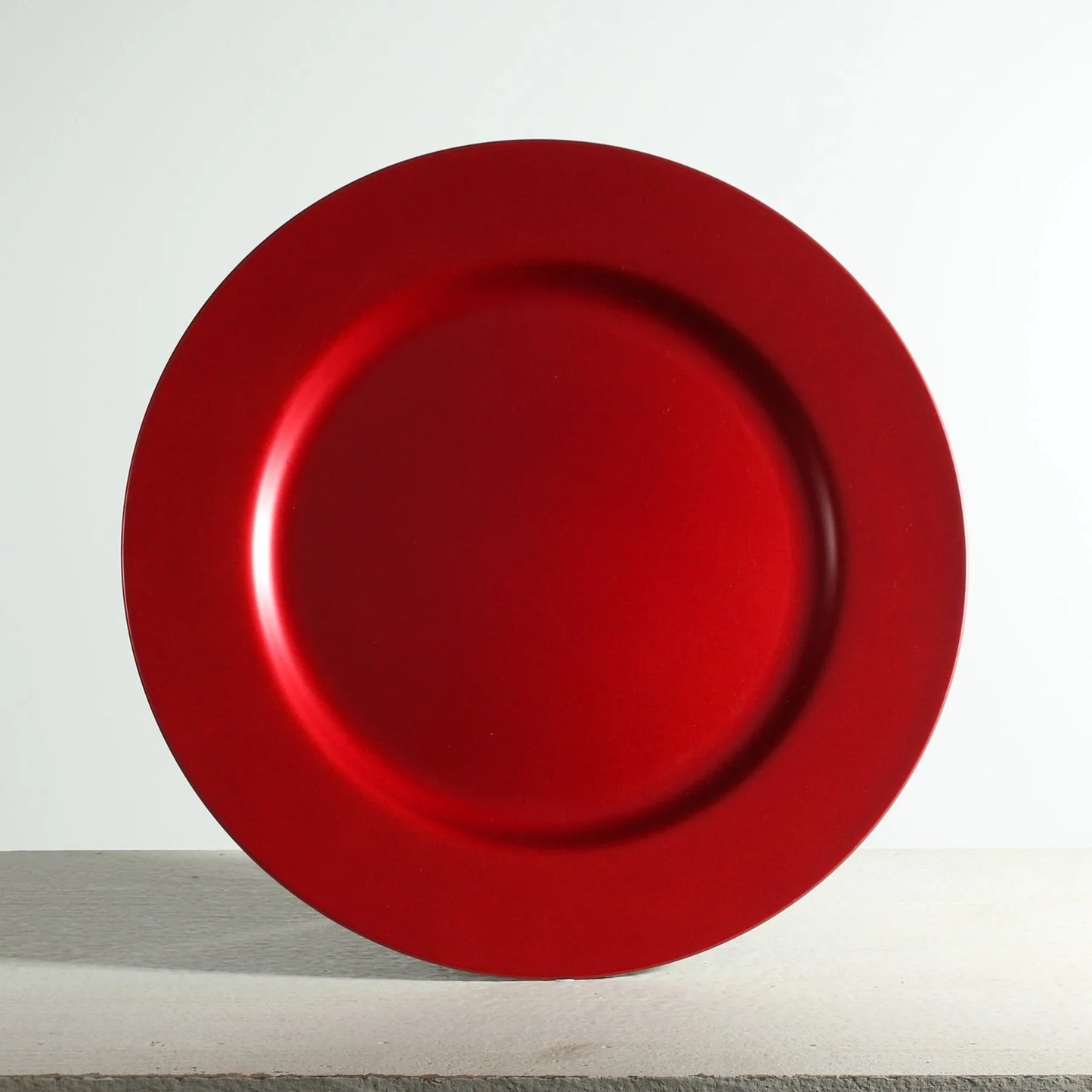 Red decorative charger plate on a neutral background, ideal for festive table settings.