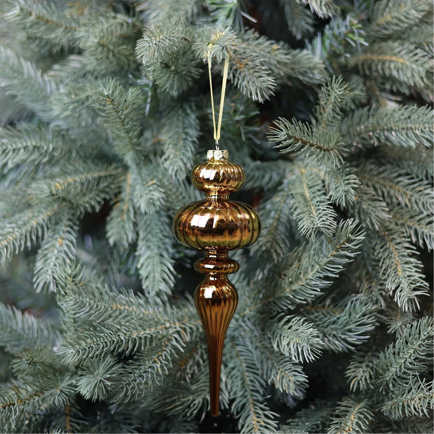 Vintage gold glass finial ornament hanging on a pine Christmas tree