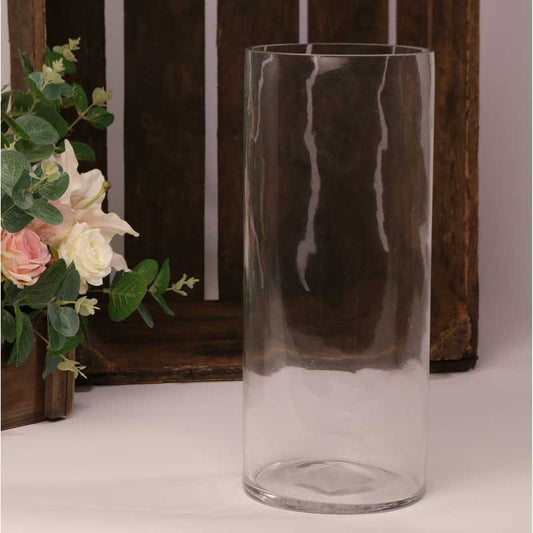 Clear glass cylinder vase with floral arrangement, rustic wooden background