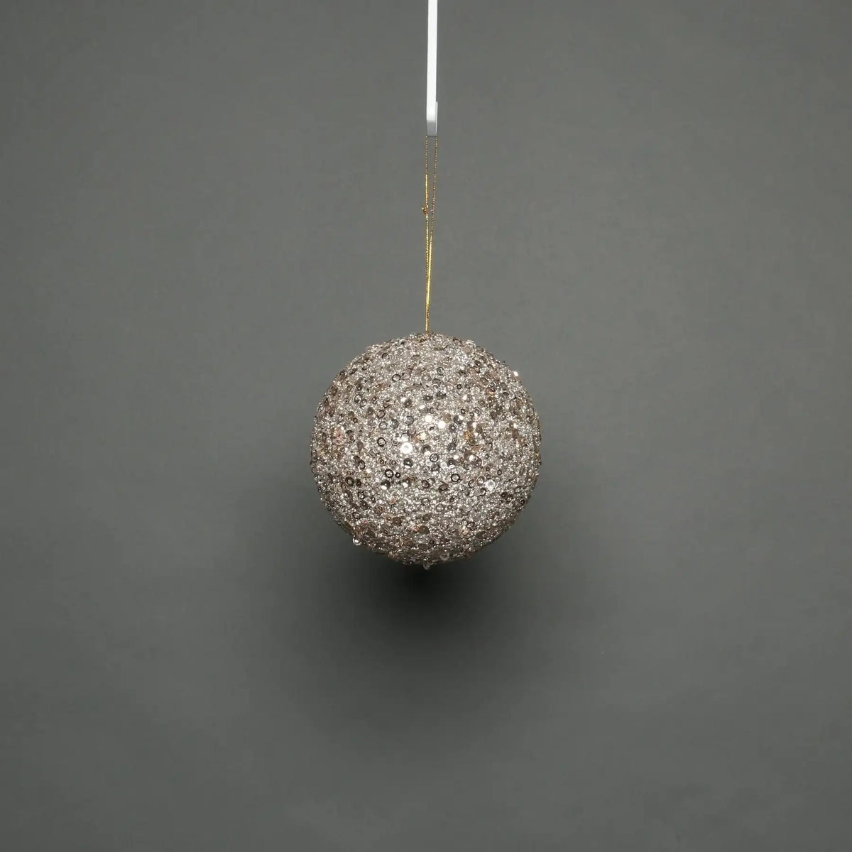 Sparkling silver sequin Christmas bauble hanging on gold string, festive holiday decoration for tree or home