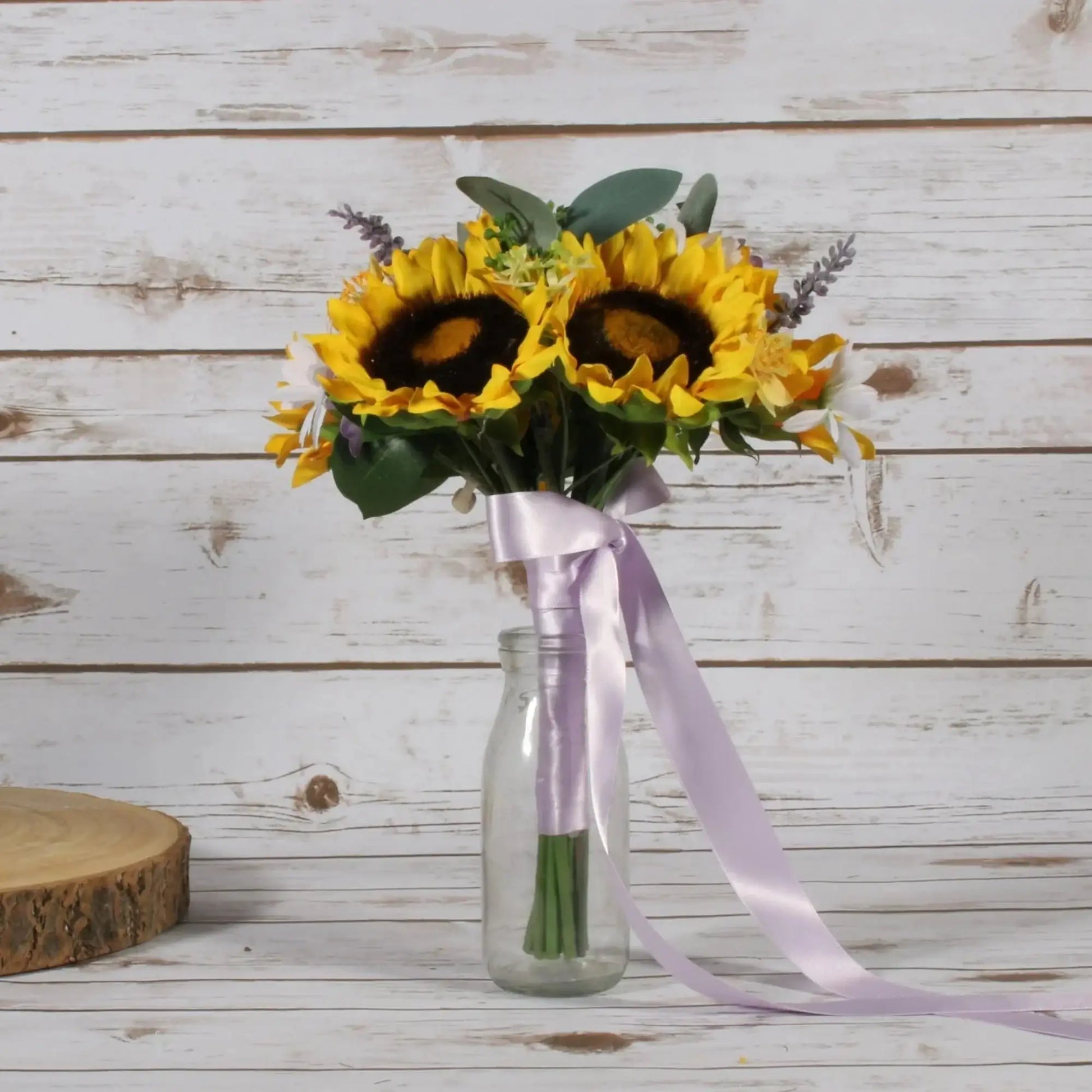 Sunflower bouquet with lavender ribbon in glass vase on rustic wood background