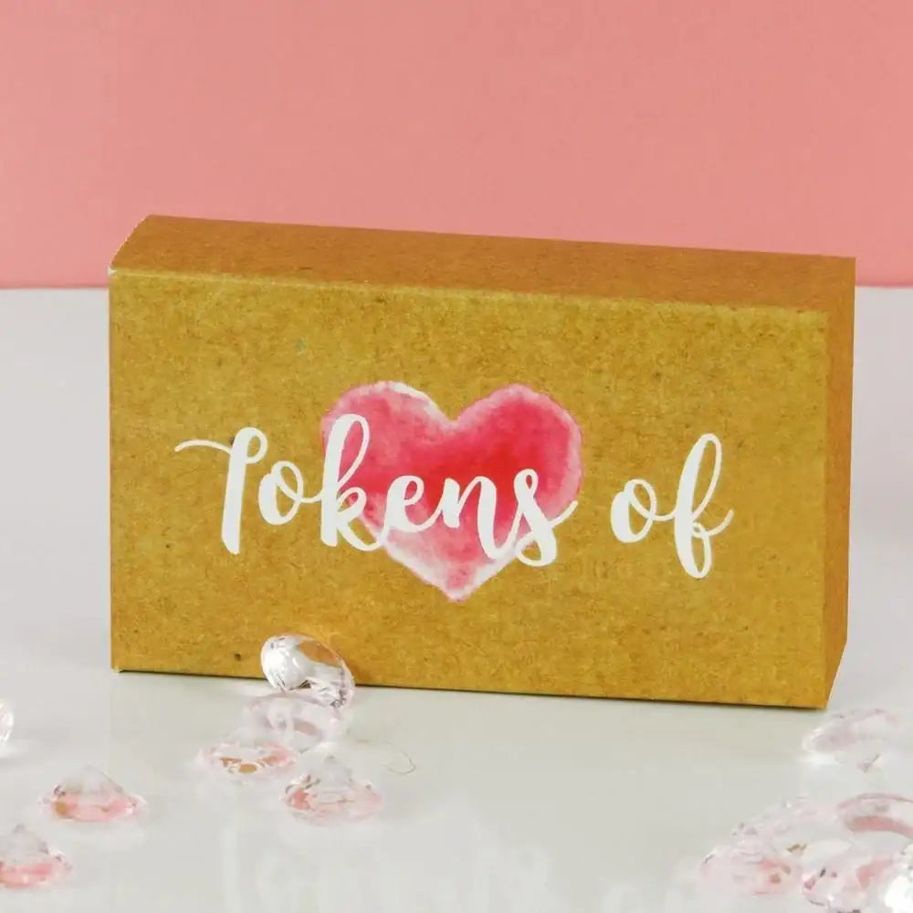Gift box with pink heart graphic and 'tokens of' text, surrounded by clear gem decorations.