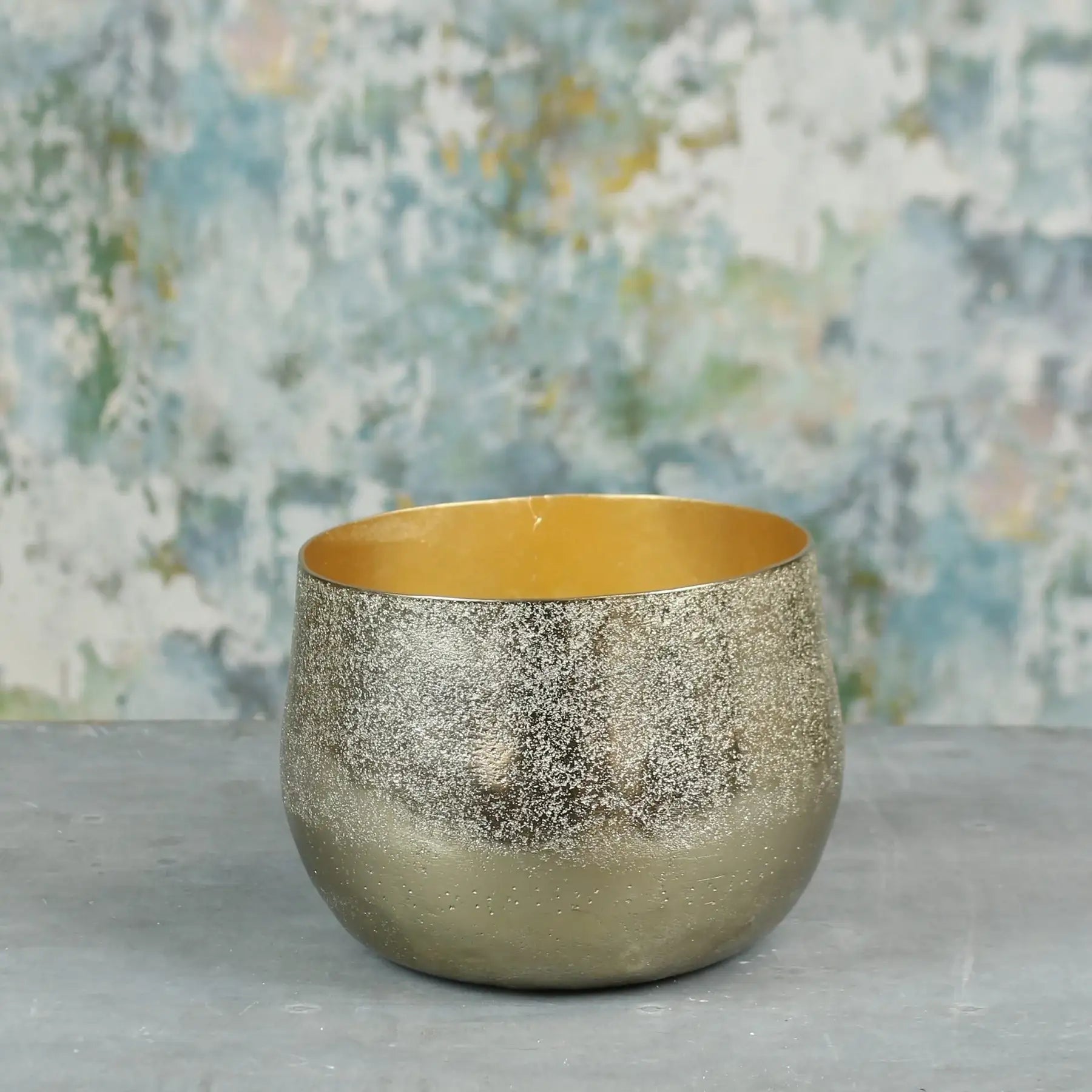 Gold metallic decorative bowl with textured finish on a grey surface, home decor accent