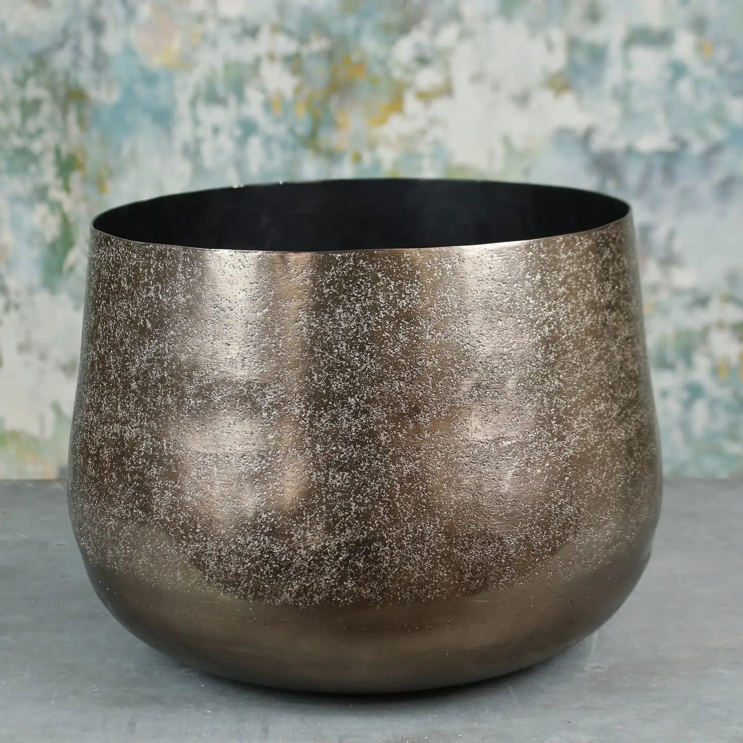 Metallic textured decorative bowl on grey surface with abstract background