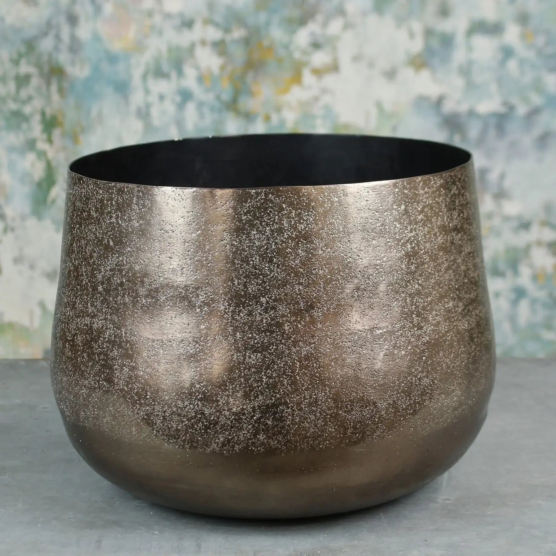 Metallic textured decorative bowl on grey surface with abstract background