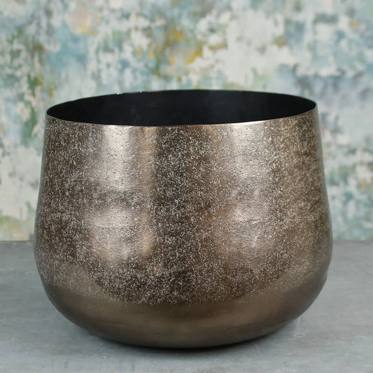 Metallic textured decorative bowl on grey surface with abstract background