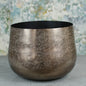 Metallic textured decorative bowl on grey surface with abstract background
