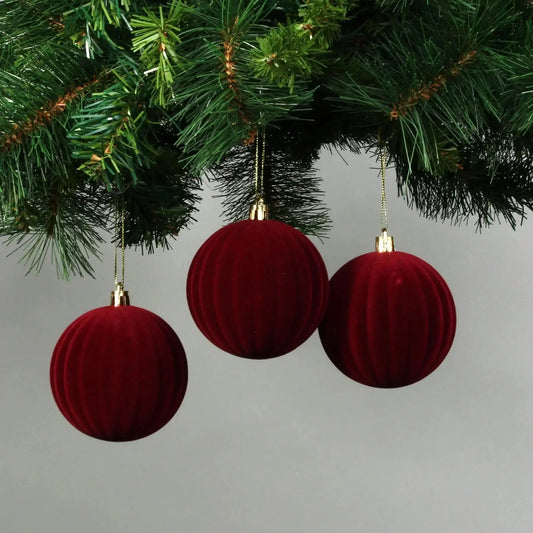 Red velvet Christmas ornaments hanging on a pine tree branch, festive holiday décor