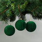 Emerald green velvet Christmas ornaments hanging on a tree branch, perfect for holiday home décor and festive celebrations.