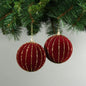Red velvet Christmas ornaments with gold glitter stripes hanging on tree branches
