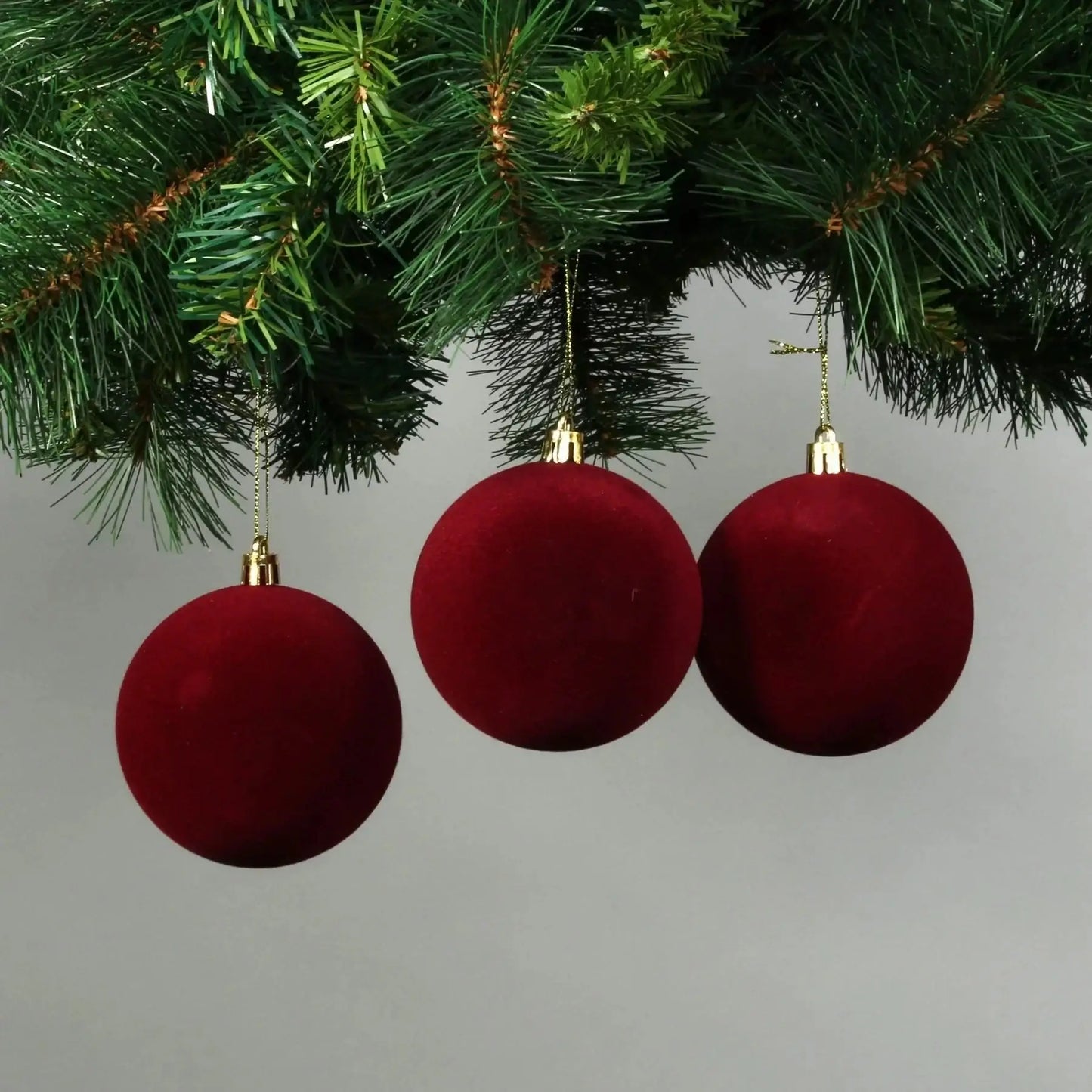 Red velvet Christmas ornaments hanging on pine branches, festive holiday décor for tree decoration