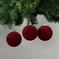 Red velvet Christmas ornaments hanging on pine branches, festive holiday décor for tree decoration