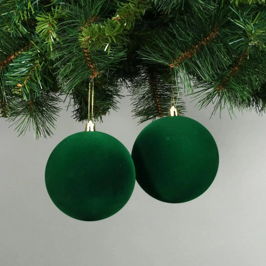Emerald green velvet Christmas baubles hanging on a pine tree branch, festive holiday decor