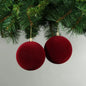 Red velvet Christmas ornaments hanging on a green tree branch, perfect for holiday home décor and festive celebrations.