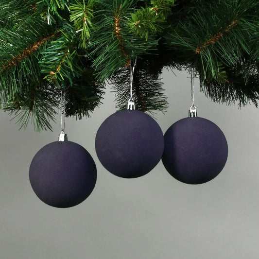 Three matte purple Christmas baubles hanging on a green tree branch, perfect for festive home décor.