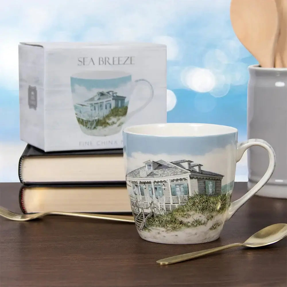 Sea Breeze fine china mug with beach house design, displayed on a table with books and gold spoons