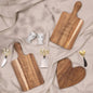 Wooden wedding-themed cutting boards, cheese knives, and egg cups on beige fabric.