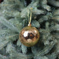 Gold Christmas ornament hanging on green tree branch for holiday decoration
