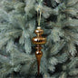 Vintage gold glass finial ornament hanging on a pine Christmas tree
