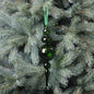 Green glass ornament hanging on a Christmas tree with silver pine needles