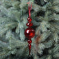 Red glass Christmas ornament hanging on pine tree, festive holiday decor