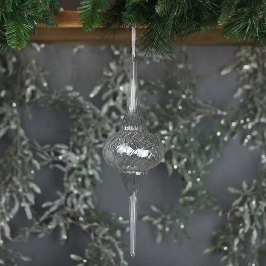 Clear glass Christmas tree ornament hanging from pine garland with silver holiday decor