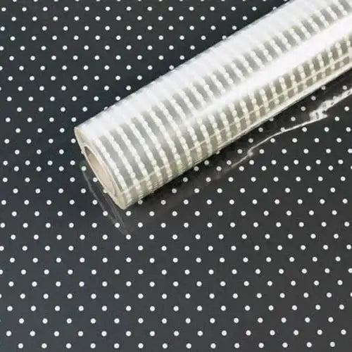 Polka dot cellophane gift wrap roll on black background, ideal for gift packaging and crafts.