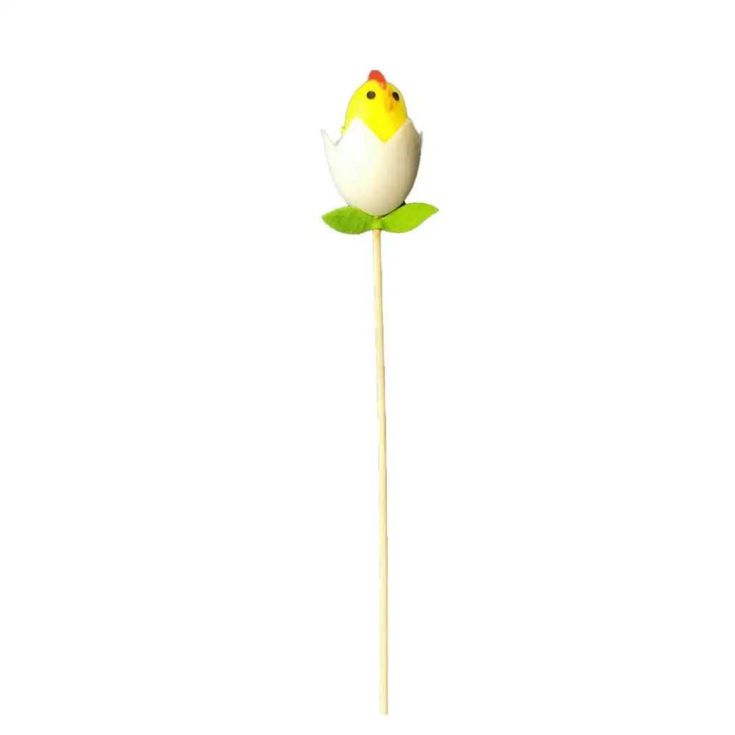 Yellow chick ornament in cracked egg with green leaves on a stick, festive home décor