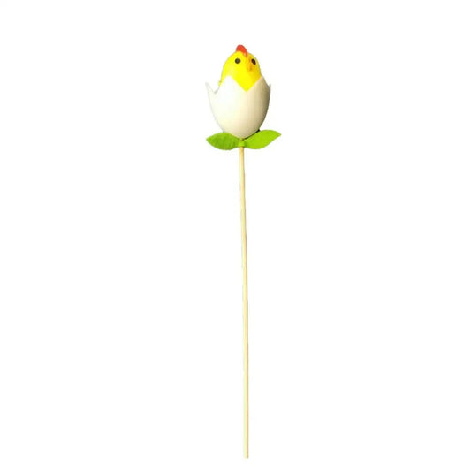 Yellow chick ornament in cracked egg with green leaves on a stick, festive home décor