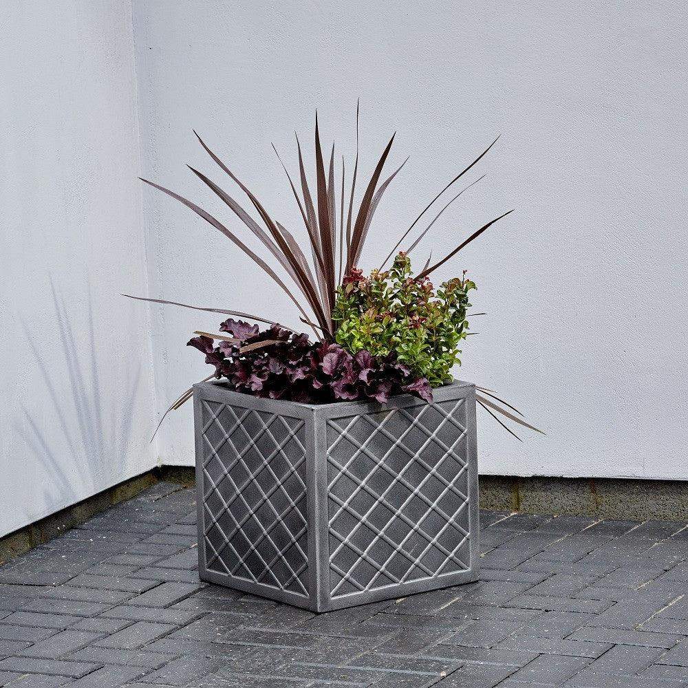 Modern square outdoor planter with geometric lattice pattern and mixed foliage plants on patio