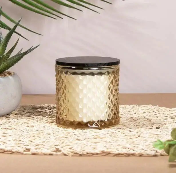 Textured glass candle with black lid on woven mat, home décor, indoor plant beside