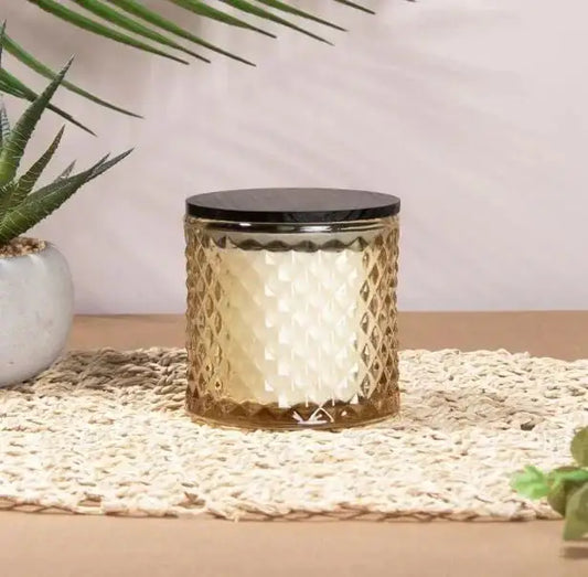 Textured glass candle with black lid on woven mat, home décor, indoor plant beside