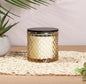 Textured glass candle with black lid on woven mat, home décor, indoor plant beside
