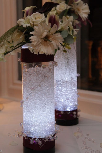 Elegant illuminated vase centerpieces with white flowers and decorative beads, perfect for home décor or special occasions.