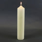 Lit white pillar candle for home décor and celebrations, perfect for creating cozy ambiance.