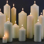Lit white pillar candles in various sizes for cozy home décor and celebration ambiance