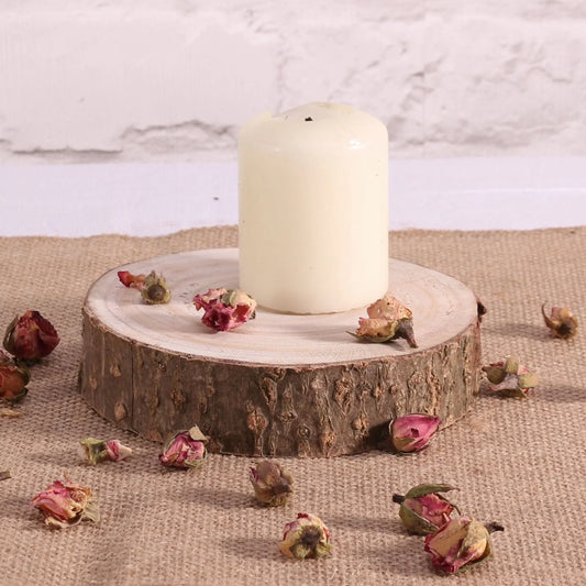 White pillar candle on rustic wood slice with dried rosebuds, home décor accent