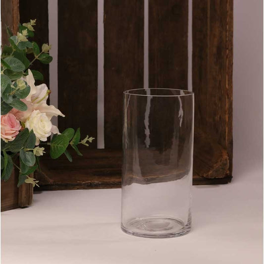 Clear glass cylinder vase with floral arrangement and rustic wood background